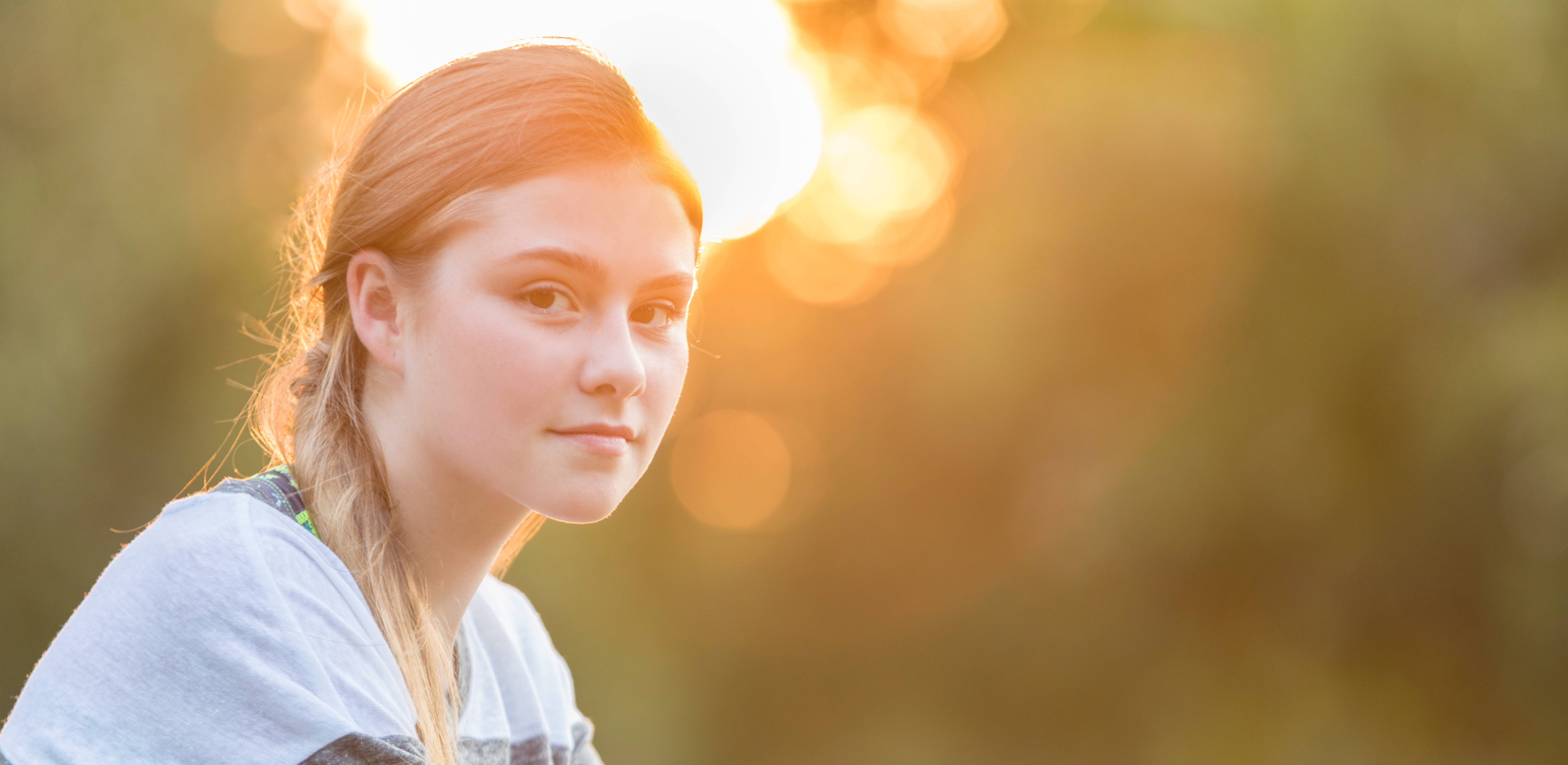 Porträt von jungem Mädchen draußen im Sonnenschein. Die Initiative 'Stark im Sturm' hilft Kindern und Jugendlichen von psychisch und suchtkranken Eltern.